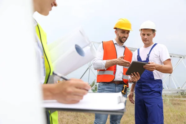 Professional engineers working on installation of electrical substation outdoors