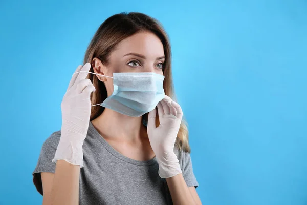 Woman Medical Gloves Putting Protective Face Mask Light Blue Background — Stock Photo, Image