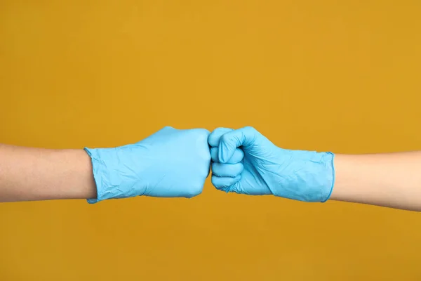 医療用手袋の医師は黄色の背景に拳バンプを作る クローズアップ — ストック写真