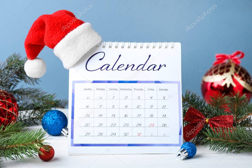 Flip calendar with Santa hat and Christmas decor on white wooden table. Holiday countdown