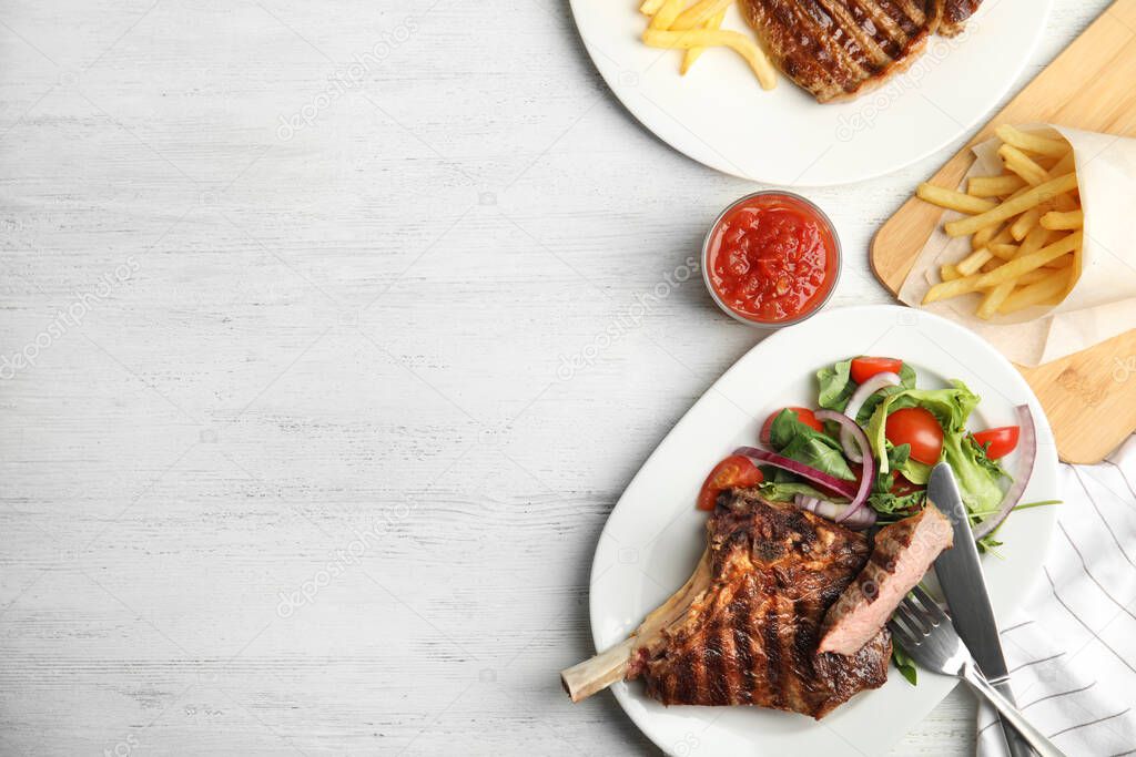Grilled steak served on white wooden table, flat lay. Space for text