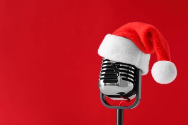 Kırmızı arka planda Noel Baba şapkalı Retro mikrofon, mesaj için boşluk. Noel müziği