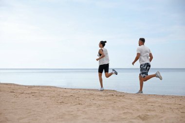 Kumsalda birlikte koşan bir çift, mesajlaşmak için yer. Vücut eğitimi
