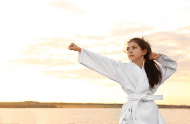 Gün batımında nehirde karate yapan kimonolu tatlı bir kız.