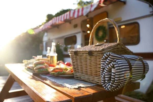 Rieten Mand Met Picknickdeken Houten Tafel Bij Trailer Kampeerseizoen — Stockfoto