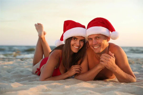 Boldog Pár Mikulás Sapkával Parton Karácsonyi Vakáció — Stock Fotó