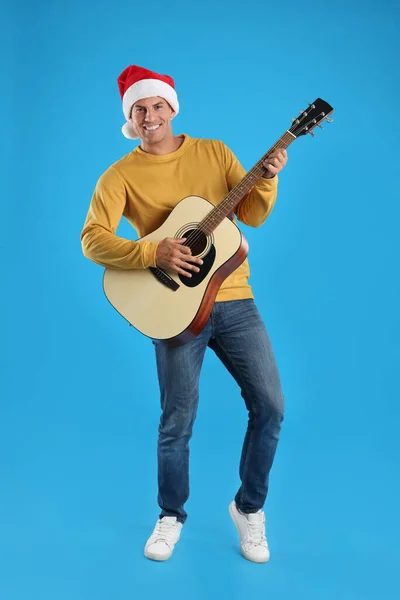 Людина Капелюсі Санта Грає Акустичній Гітарі Світло Блакитному Фоні Різдвяна — стокове фото