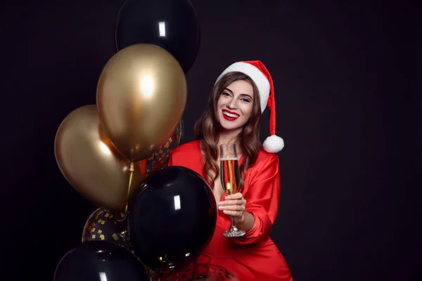 Noel Baba Şapkalı Balonlu Siyah Arka Planda Bir Bardak Şampanyası — Stok fotoğraf