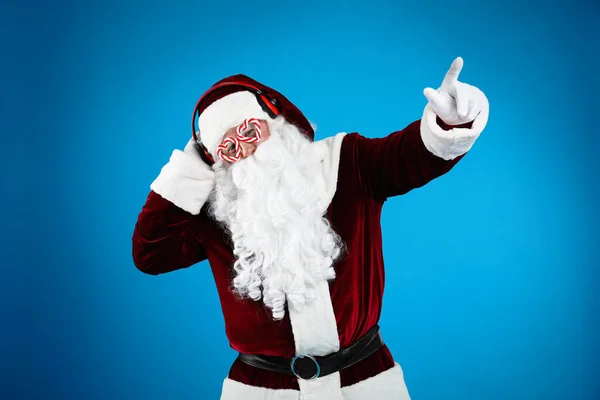 Święty Mikołaj Słuchawkami Słuchającymi Świątecznej Muzyki Niebieskim Tle — Zdjęcie stockowe
