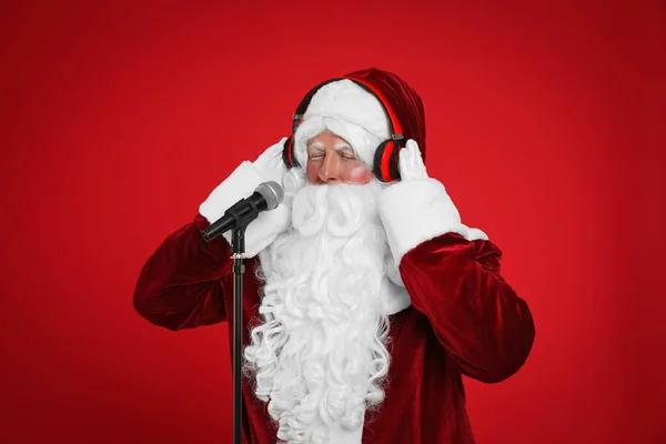 Kırmızı Arka Planda Mikrofonu Kulaklığı Olan Noel Baba Noel Müziği — Stok fotoğraf