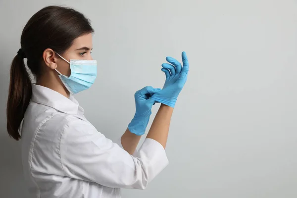 Doctor Protective Mask Putting Medical Gloves Light Grey Background Space — Stock Photo, Image