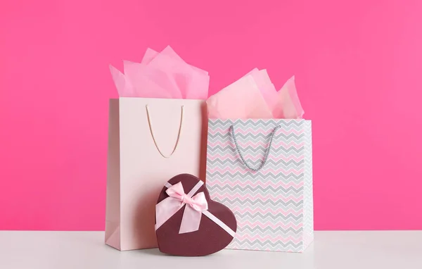 粉红背景下白色桌子上的礼品袋和礼盒 — 图库照片