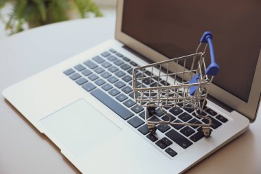 İnternet alışverişi. İçerideki masada küçük el arabası olan dizüstü bilgisayar, yakın plan.