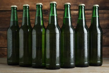 Ahşap masada yeşil bira şişeleri