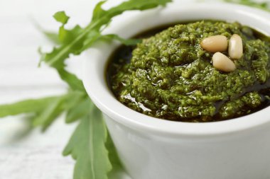 Bir kase lezzetli pesto ve roka beyaz masada, yakın plan.