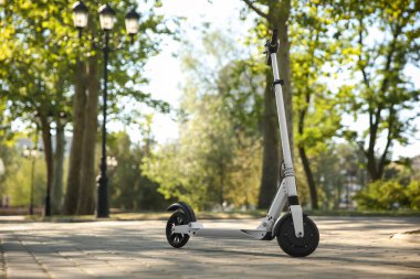Modern electric kick scooter outdoors on sunny day clipart