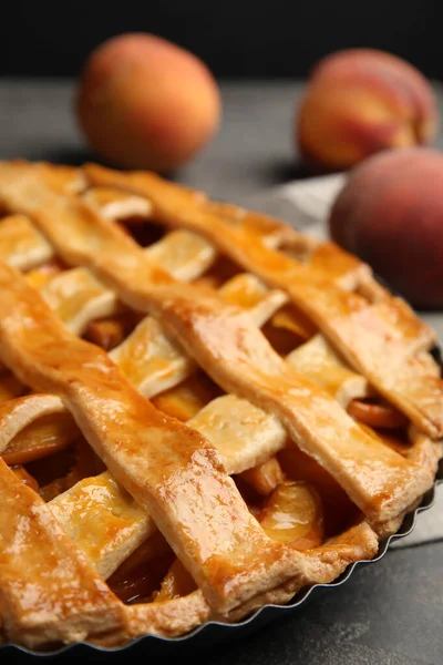 Delicious fresh peach pie on grey table, closeup