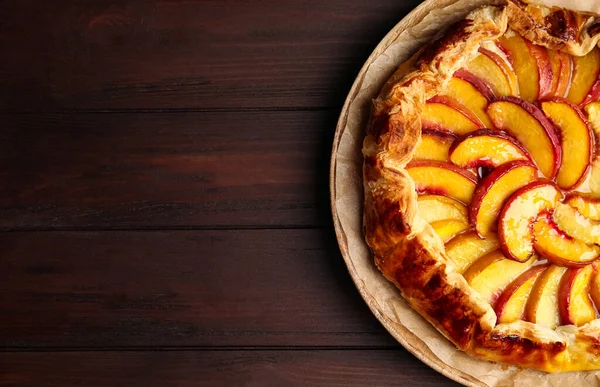 Delicious fresh peach pie on wooden table, top view. Space for text