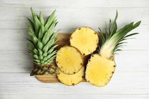 Slices of fresh pineapple on white wooden table, flat lay