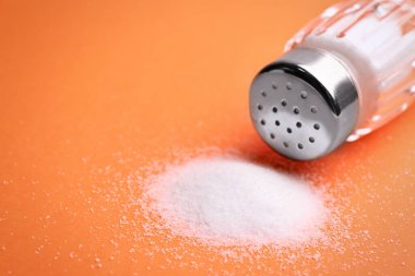 Turuncu arka planda tuzluk ve karıştırıcı, yakın plan. Metin için boşluk
