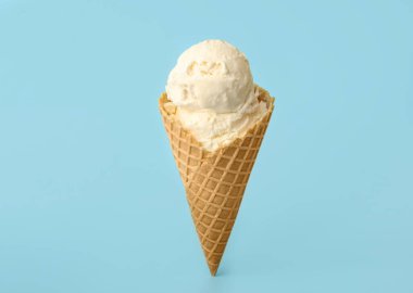 Açık mavi arka planda waffle külahında leziz dondurma.