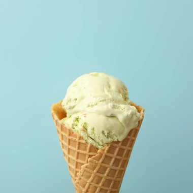 Açık mavi arka planda waffle külahında leziz dondurma, yakın plan.
