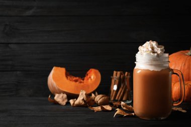 Siyah ahşap masada lezzetli balkabaklı latte. Metin için boşluk