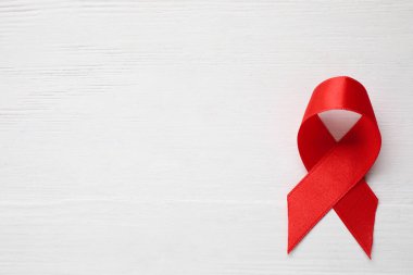 Beyaz ahşap arka planda kırmızı kurdelenin üst görüntüsü, metin için boşluk. AIDS Hastalığı Farkındalığı