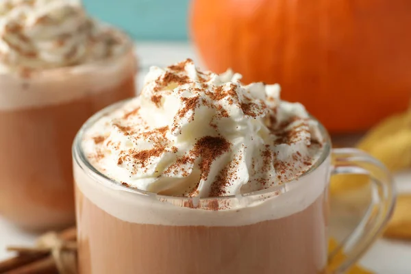 Delicious pumpkin latte with whipped cream on table, closeup