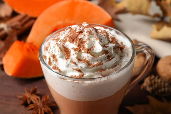 Delicious pumpkin latte with whipped cream on table, closeup