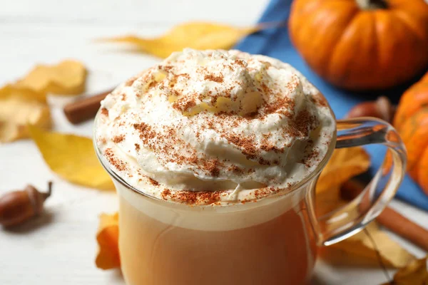 Delicious pumpkin latte on white table, closeup