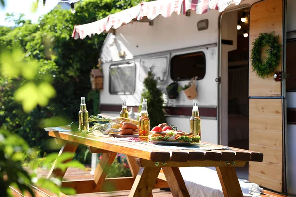 阳光明媚的日子里 在汽车家附近的木制餐桌上放着食物和啤酒瓶 野营季节 — 图库照片