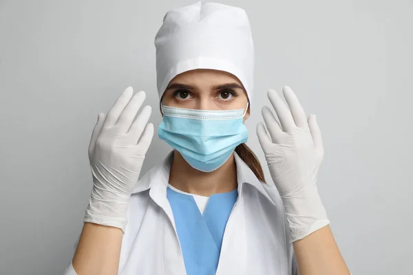 ライトグレーの背景に対する保護マスクと医療用手袋の医師 — ストック写真