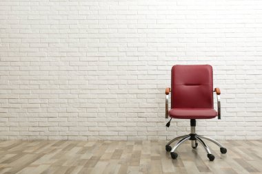 Beyaz tuğlalı duvarın yanında rahat bir ofis sandalyesi. Metin için boşluk