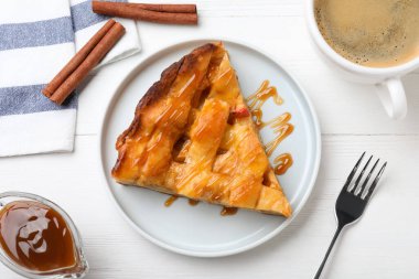 Beyaz ahşap masada kahve ile servis edilen geleneksel elmalı turta dilimi.