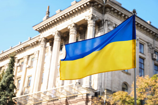 National flag of Ukraine fluttering near building on sunny day