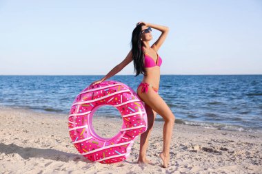 Plajda şişme yüzüklü pembe bikinili güzel bir kadın.