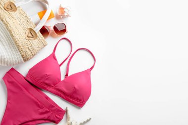 Güzel pembe bikini ve beyaz arka planda plaj aksesuarları, düz yatış. Metin için boşluk
