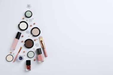 Işık arka planında dekoratif kozmetik ürünlerin Noel ağacı şekli, metin için yeri olan düz bir yer. Kış bakımı