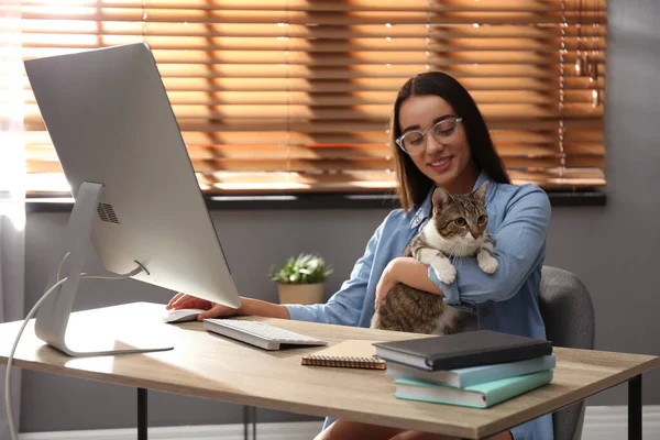 一个带着猫在桌上电脑上工作的年轻女人 总部概念 — 图库照片
