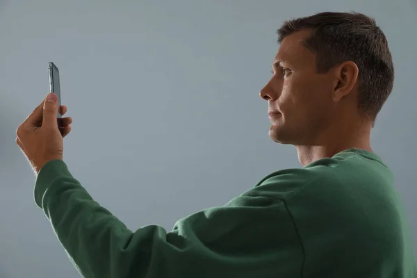 Muž Odemykání Smartphone Obličejovým Skenerem Šedém Pozadí Biometrické Ověření — Stock fotografie