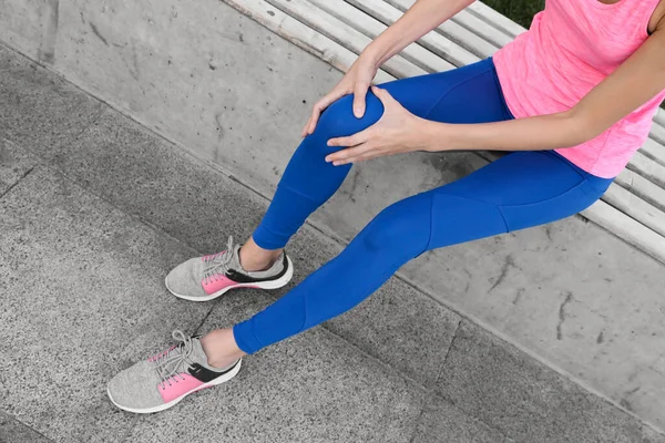 スポーツウェアの若い女性が膝の問題を抱えて屋外で クローズアップ — ストック写真