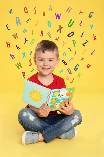 Netter Kleiner Junge Liest Buch Umgeben Von Verschiedenen Buchstaben Auf — Stockfoto