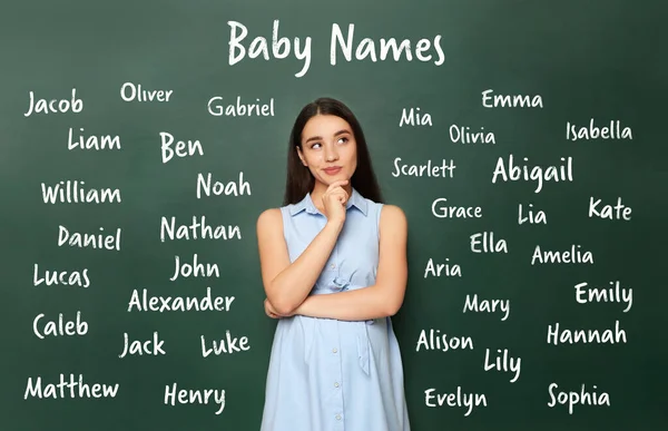 Thoughtful pregnant woman choosing name for her child. Future mother near green chalkboard with different names