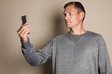 Adam bej arka planda yüz tarayıcı ile akıllı telefonun kilidini açıyor. Biyometrik doğrulama