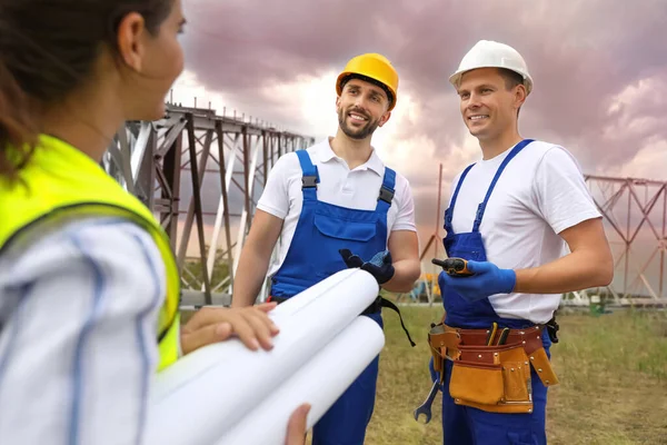 Professional engineers working on installation of electrical substation outdoors