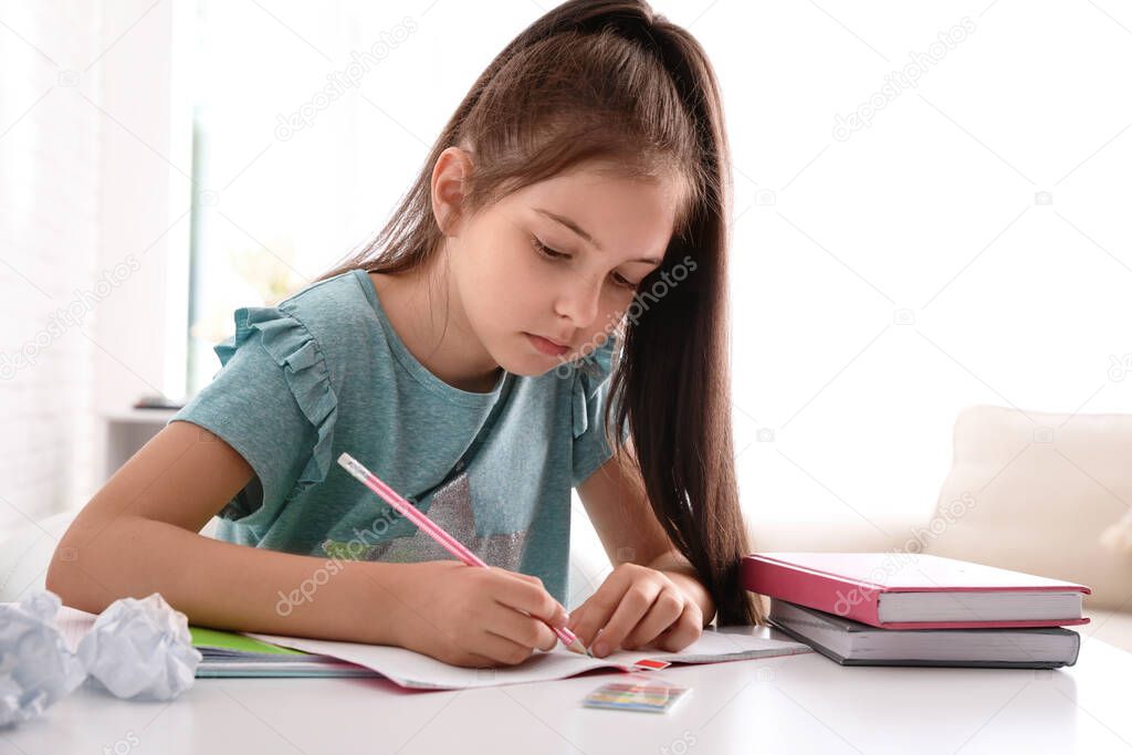 Pretty preteen girl doing homework at table