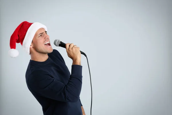 Емоційний Чоловік Капелюсі Санта Клауса Співає Мікрофоном Світло Сірому Фоні — стокове фото