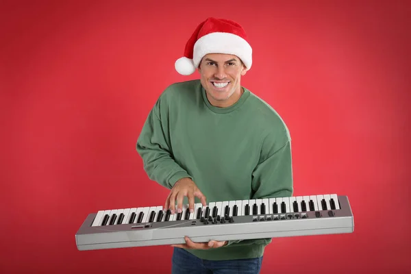 Man Santa Hat Грає Синтезаторі Червоному Фоні Різдвяна Музика — стокове фото