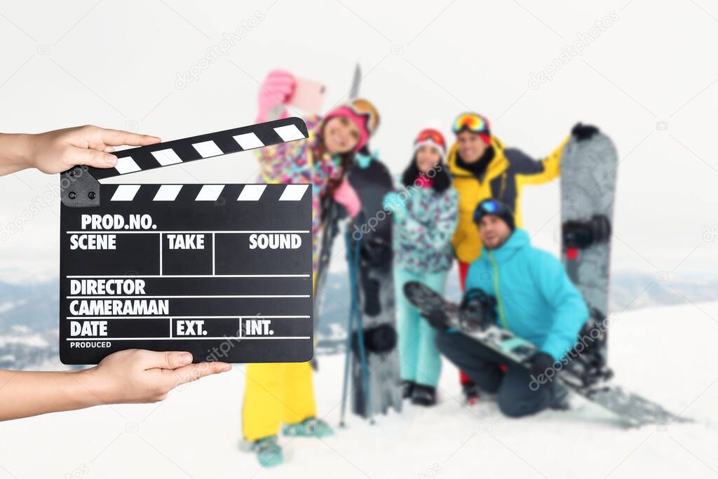 Assistant  holding clapperboard and people in snowy mountains, closeup. Cinema production 
